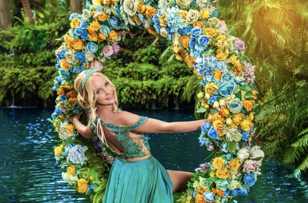 villas photoshoot at Villa Turquesa in Homestead FL – quinceañera swinging on a circular floral swing above turquoise water surrounded by tropical greenery.