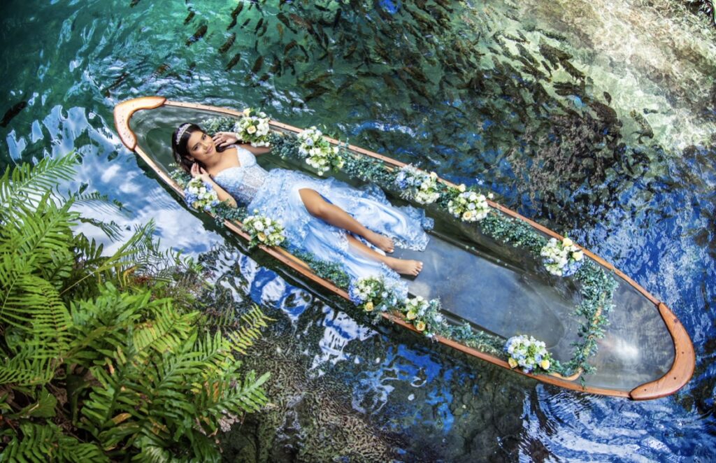Villas photoshoot at Secret Gardens Miami with a quinceañera floating in a clear kayak decorated with flowers.