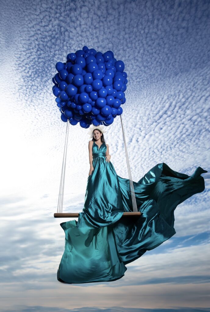 Quinceañera in a teal gown on a balloon swing during a The Barn 305 photoshoot.