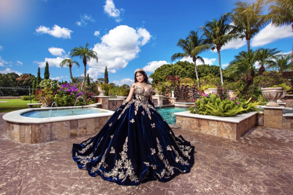 Villas photoshoot at Villa Toscana Miami with a quinceañera in a navy blue ball gown posing in the elegant garden fountain area.