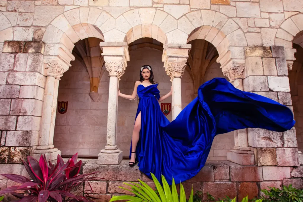 Castle quince photography at the Spanish Monastery: royal blue gown with flowing train framed by triple stone arches.
