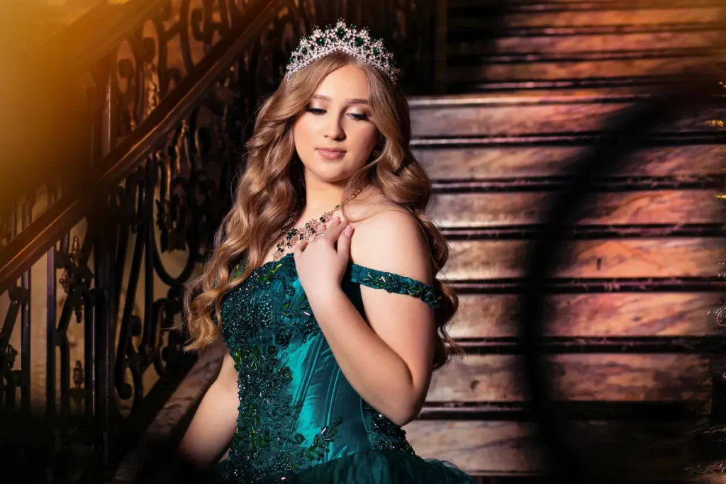 Castle quinceañera photos at The Cruz Building: emerald gown and tiara on marble staircase with golden light.